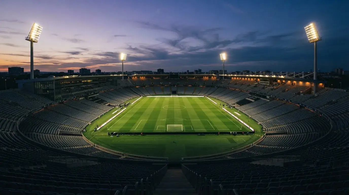 Een leeg voetbalstadion met lichtmasten bij schemering